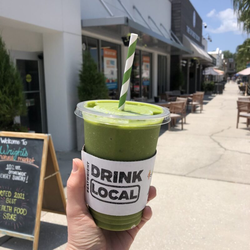 Green smoothie with Drink Local Wrapper outside Cafe